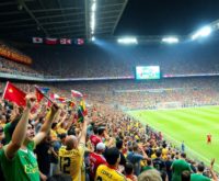 Excited soccer fans cheering at a packed stadium.