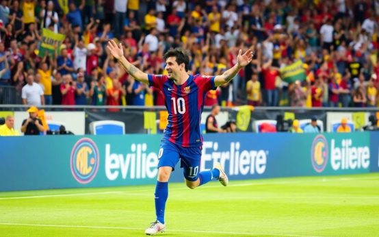 Lionel Messi celebrates a goal with fans cheering.