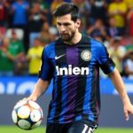 Lionel Messi dribbling the ball on a soccer field.